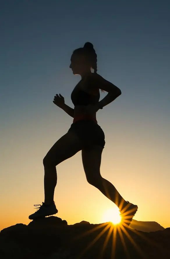 silhouette of man jumping on rocky mountain during sunset